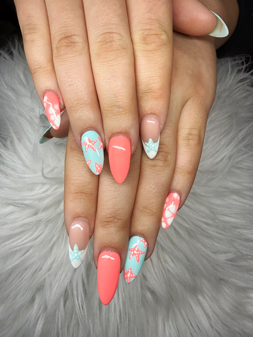 Coral and aqua almond nails with starfish, seashell and beach-inspired French tip art by Chic Nail and Head Spa
