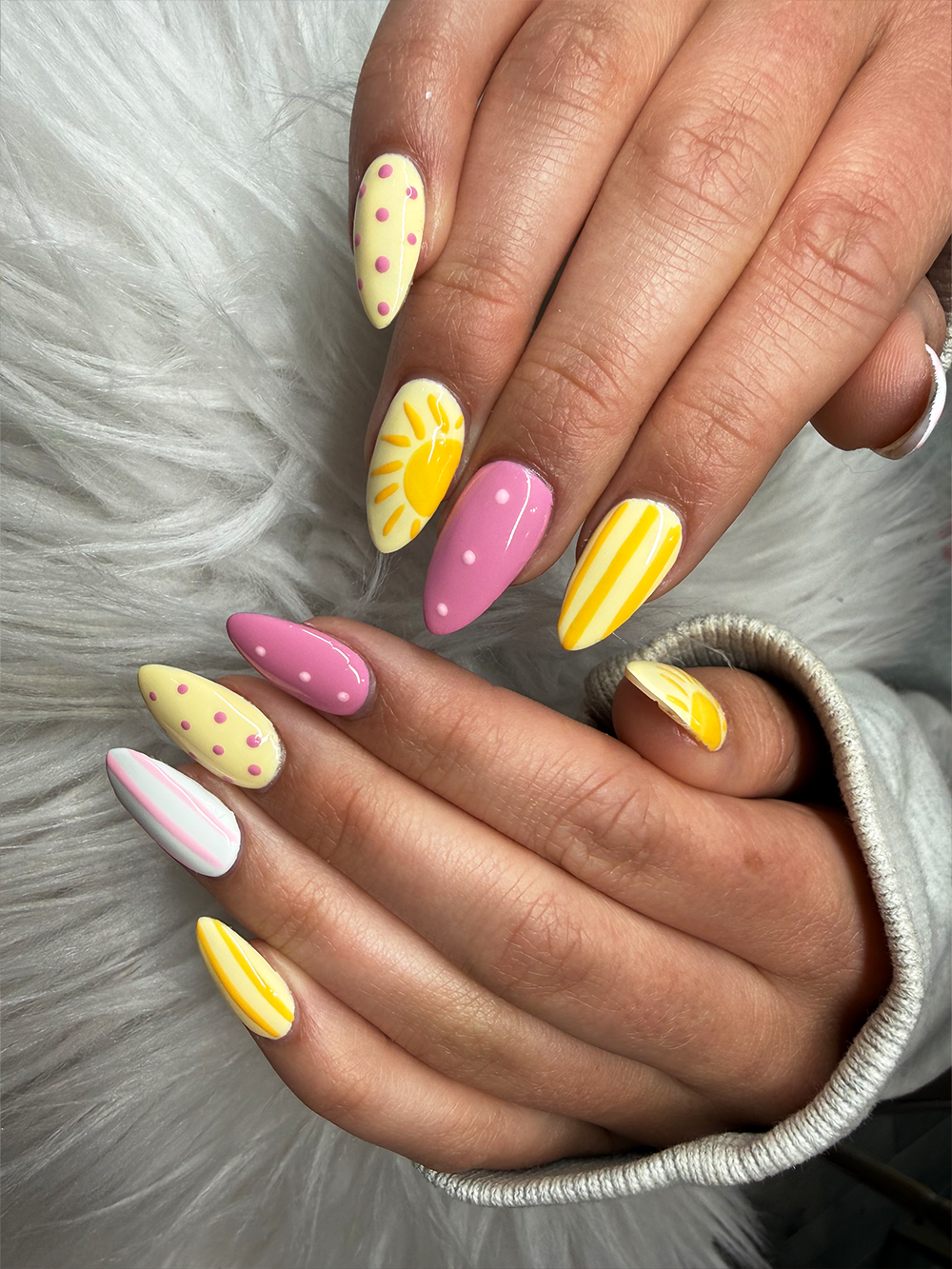 Pink and yellow almond nails with sunshine art, polka dots and striped summer patterns by Chic Nail and Head Spa
