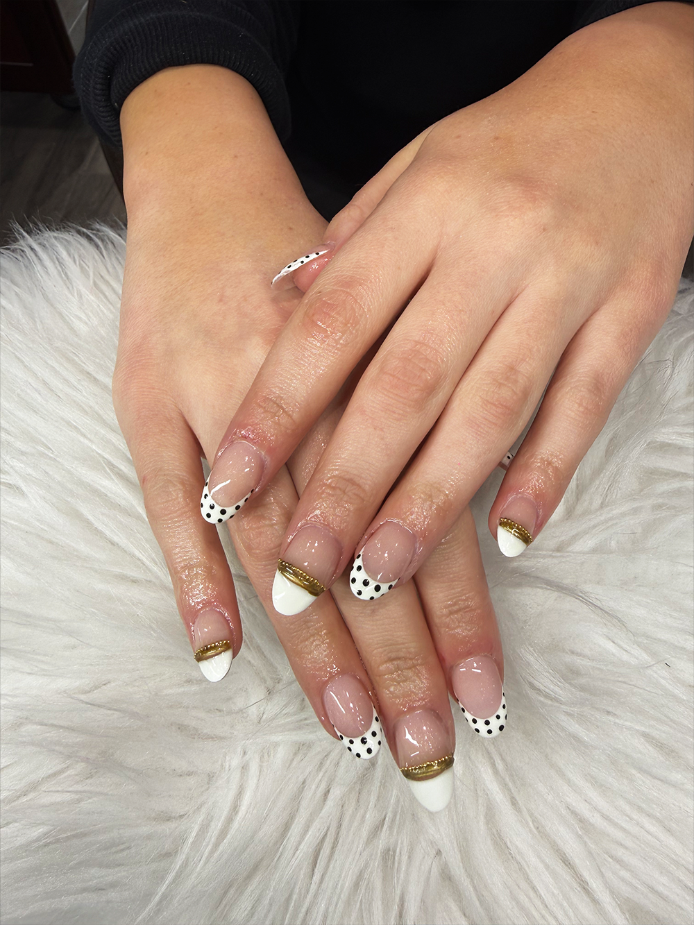 Short nude nails with white French tips, black polka dots and metallic gold trim by Chic Nail and Head Spa